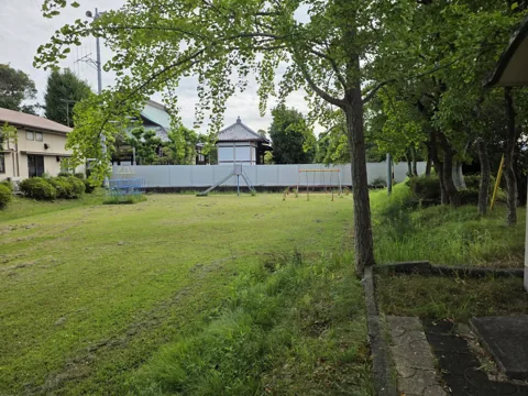 一番町公園：芝生広場越しに見た奥の遊具（雲梯・ジャングルジム・ブランコ）