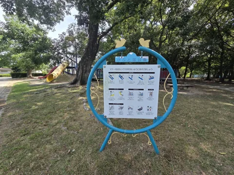 かぶと塚公園：遊具広場の利用マナー看板。奥にチューブスライダー