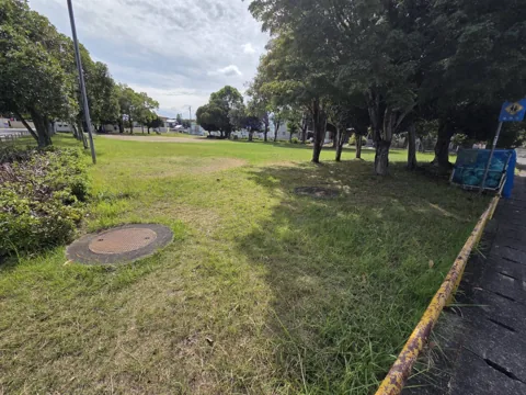 経塚公園：道路沿いの柵と園内の芝生