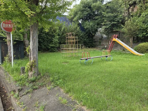只来下公園：入口側から見た園内。防火水そうの標識、ジャングルジムとすべり台