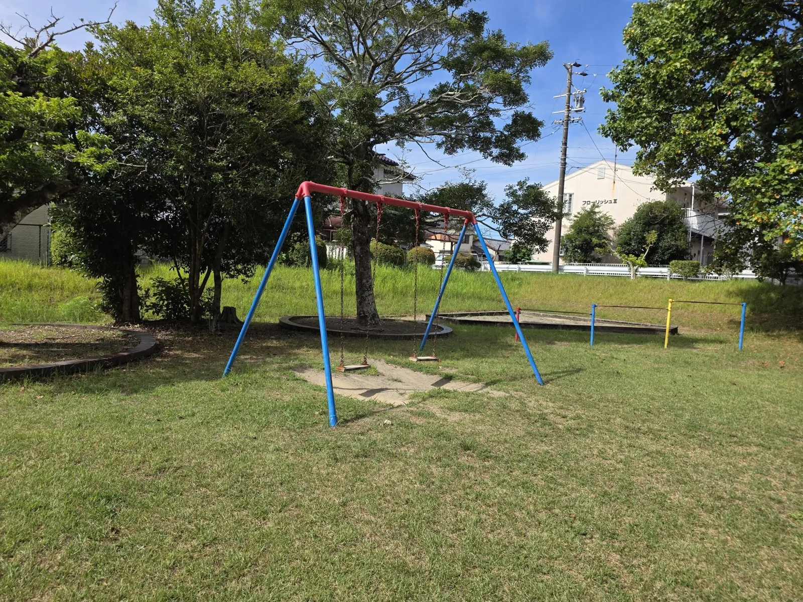 的場公園:ブランコと砂場、奥に鉄棒。芝生の広場