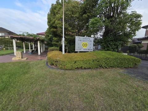 葦間公園：大きな樹木とパーゴラ、案内板のある園内
