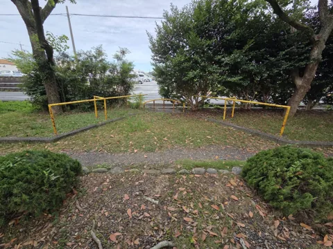 旭ヶ丘公園：道路側の入口。黄色の車止め柵と園路