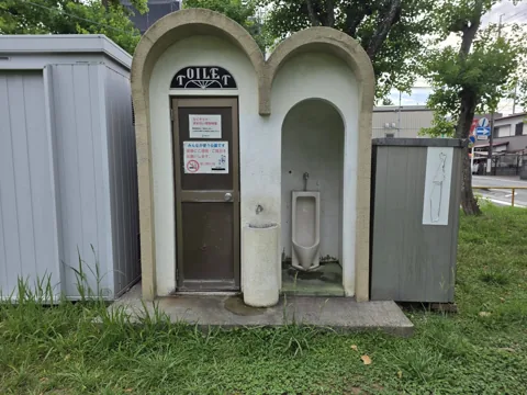 旭ヶ丘公園：トイレ外観。アーチ型の建物で、外に手洗いと小便器