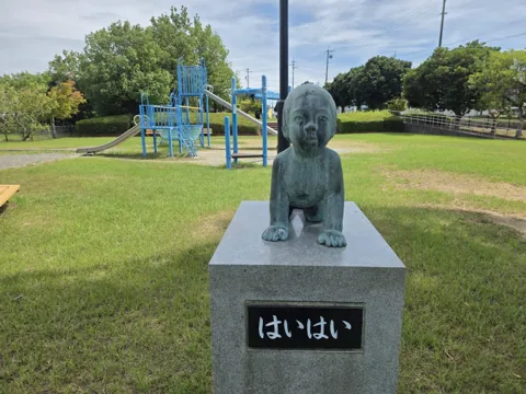 北川瀬公園：子どもの像「はいはい」。奥に複合遊具