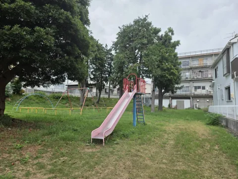 久保公園：大きな樹木の近くに立つ単体すべり台