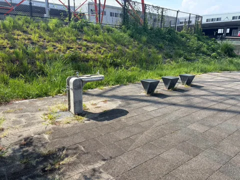 磐田ららシティ東ポケットパーク：水飲み場と舗装広場に並ぶ石製の腰掛け