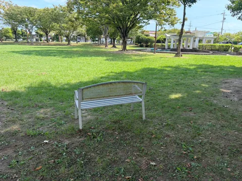 豊田香りの公園：芝生広場と時計塔を望む木陰のベンチ