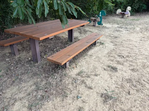 豊田原新田公園：木製テーブルとベンチ。奥にスプリング遊具