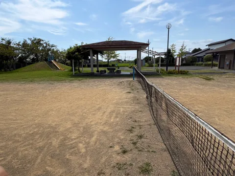 豊田森本農村公園：ネット越しに見た運動広場と休憩所